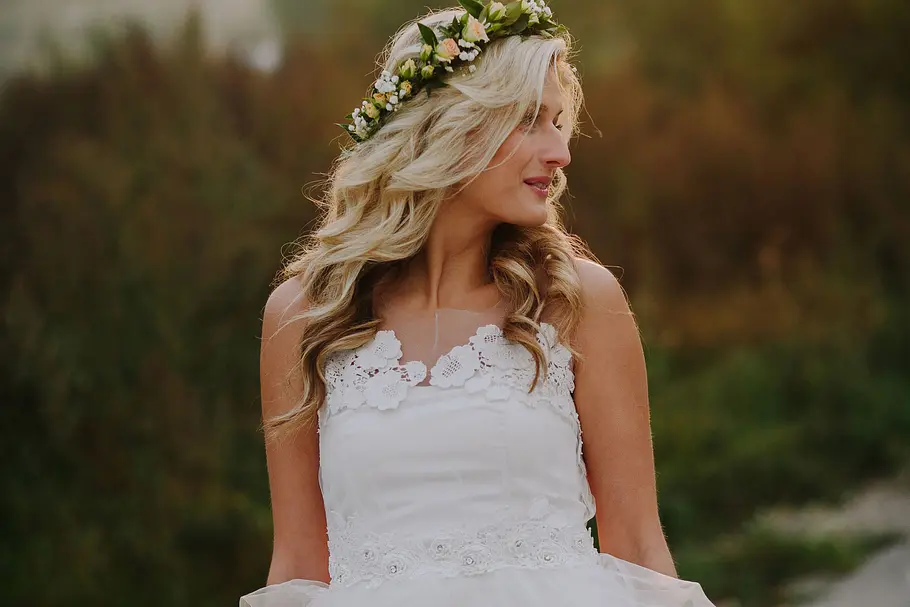 Boho-Braut mit Locken und Blumenkranz. Braut trägt passend zu ihrem gelockten Haar einen Blumenkranz.