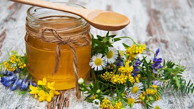Honey and wild flowers on a old wooden background - Foto: Ls9907/iStock