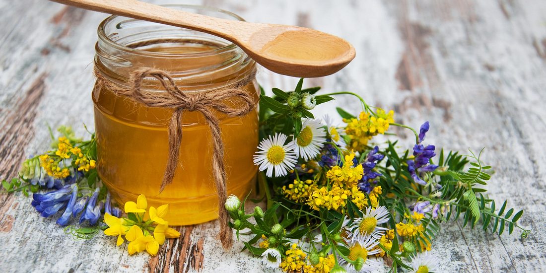 Honey and wild flowers on a old wooden background