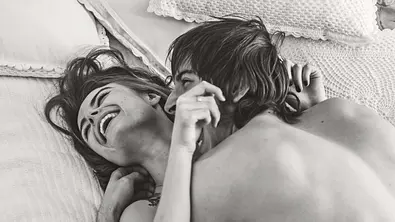 Frau und Mann liegen zusammen im Bett und lachen. - Foto: iStock/oleg66