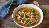 Ein Teller mit Hühnersuppe, einem Löffel und einem Lätzchen, dazu Petersiliengarnitur (Themenbild) - Foto: Angelika Heine/iStock