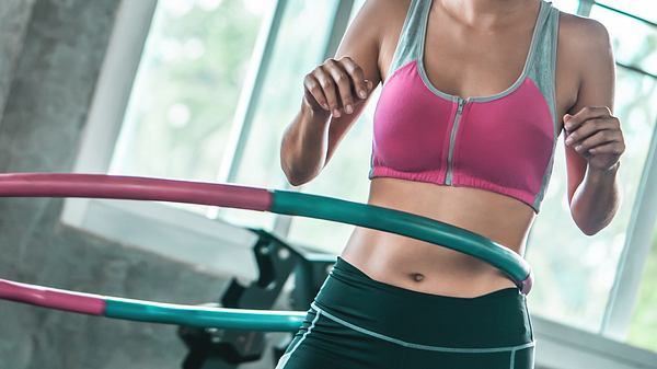 Frau im Fitnessstudio mit Hula Hoop Reifen - Foto: iStock/junce