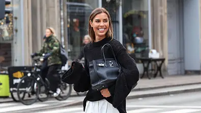 Freu mit schwarzem Oberteil und Tasche unter dem Arm - Foto: IMAGO/  ZUMA Press Wire