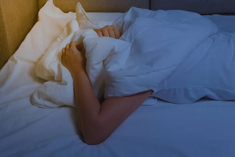Person liegt im Bett und zieht sich die Decke über den Kopf. Person liegt im Bett und zieht sich die Decke über den Kopf.