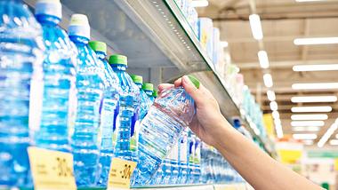 Flasche Mineralwasser von Hand aus dem Regal im Supermarkt nehmen - Foto: sergeyryzhov/iStock