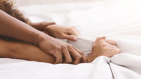 Weiße zerwühlte Bettwäsche mit vier Händen, die sich gegenseitig halten  - Foto: Prostock-Studio / iStock