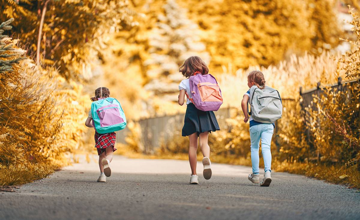 Drei Mädchen mit Rucksäcken auf dem Rücken auf dem Weg in die Kita und Schule