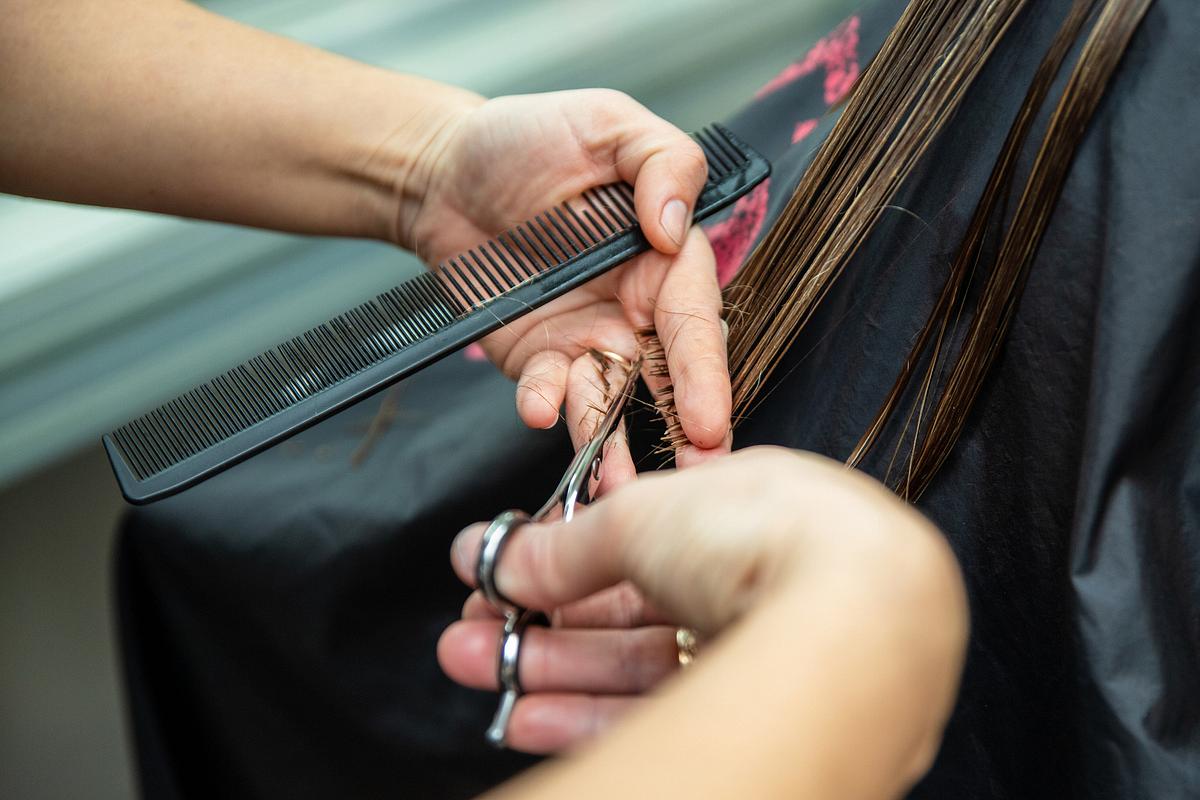 Frau sitzt beim Friseur und bekommt die Haare geschnitten