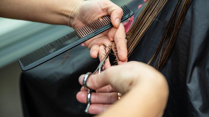 Frau sitzt beim Friseur und bekommt die Haare geschnitten - Foto: iStock/ Bota Sorin