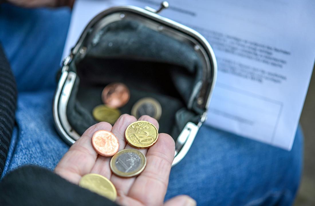 Neues Bürgergeld: Lohnt sich ein Job im Geringverdiener-Bereich noch? Frau zählt einige Euro und Cents Münzen in der Hand, Geldbörse und Mahnbrief