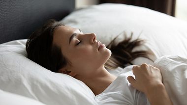 Frau liegt im Bett - Foto: iStock/fizkes