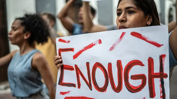 Frauen protestieren bei einem Streik und halten ein Schild mit dem Wort ENOUGH (deutsch: GENUG) hoch. - Foto: FG Trade Latin/iStock
