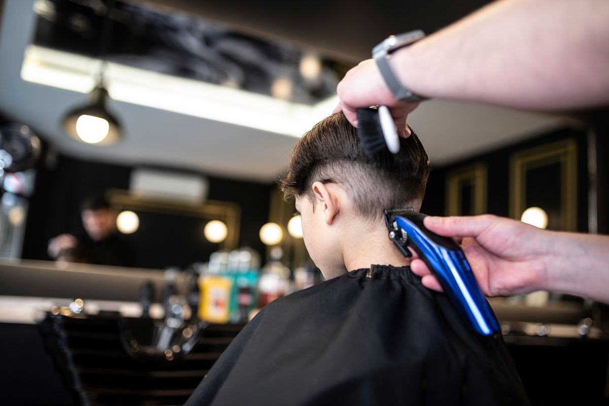 Junge bekommt vom Friseur eine angesagte neue Frisur verpasst