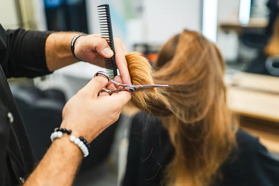 Friseur Frau von hinten, die auf einem Friseurstuhl sitzt und die Haare geschnitten bekommt