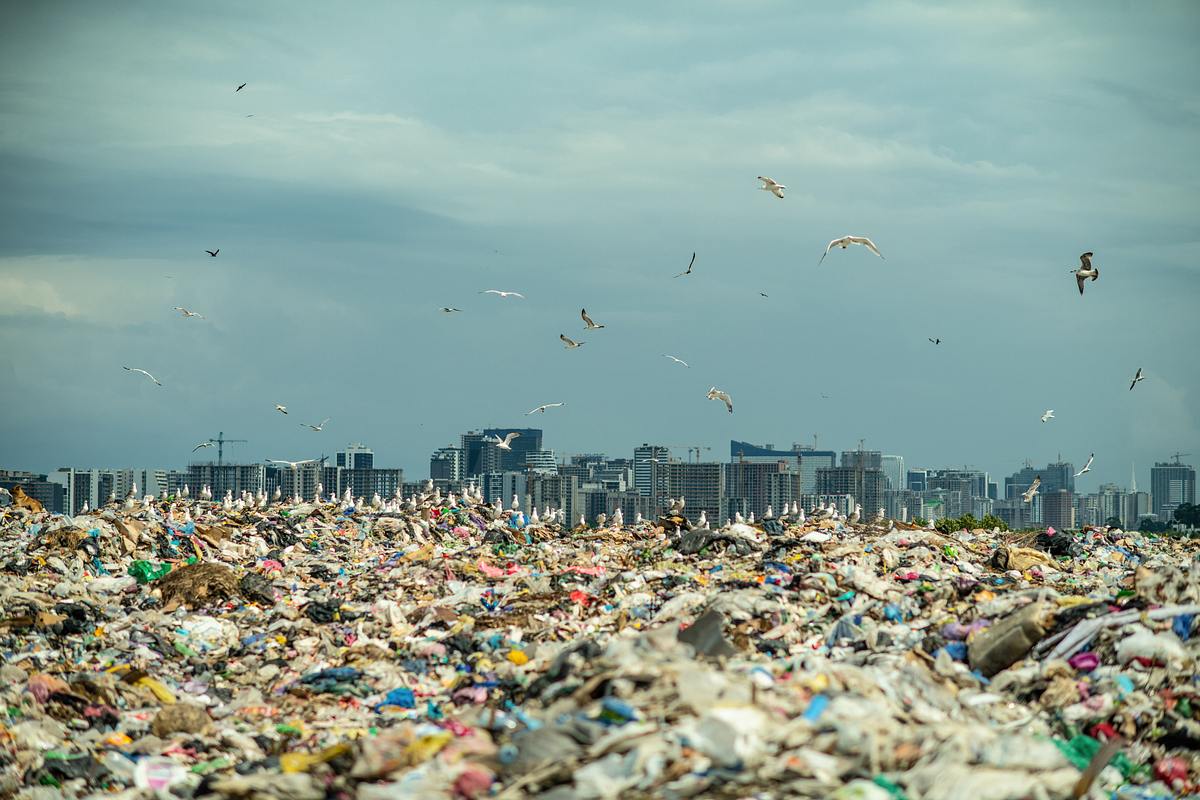  Müllhalde mit einer Stadt im Hintergrund (Themenbild)