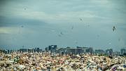  Müllhalde mit einer Stadt im Hintergrund (Themenbild) - Foto: iStock/ArtMarie