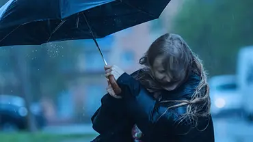 Eine Frau mit einem schwarzen Regenschirm, der vom Wind fast weg geweht wird. - Foto: iiievgeniy/iStock Eine Frau mit einem schwarzen Regenschirm, der vom Wind fast weg geweht wird. - Foto: iiievgeniy/iStock