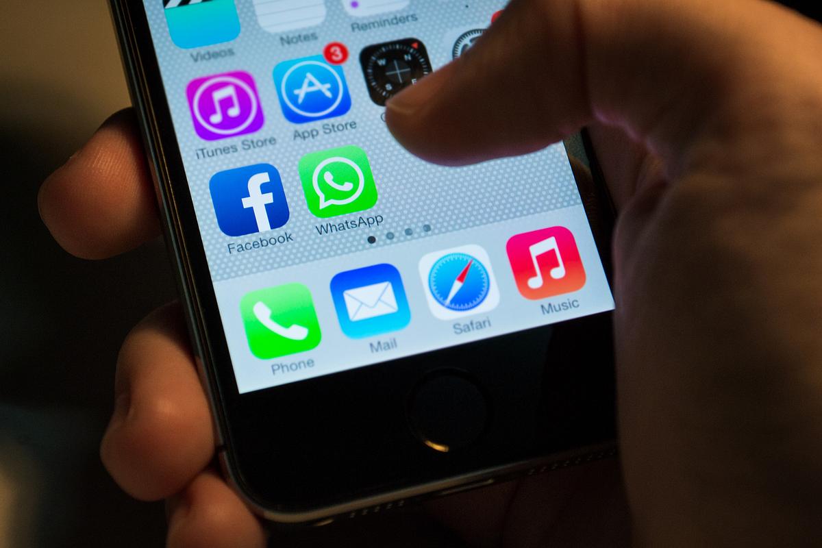 Person mit Handy in der Hand auf dem verschiedene Apps angezeigt werden