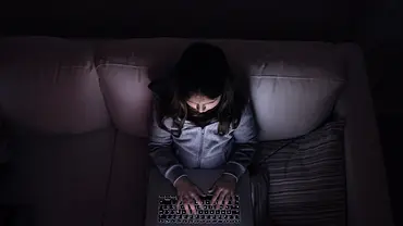 Symbolbild Deepfakes von Kindern: Mädchen sitzt im Dunkeln alleine vor dem Laptop - Foto: iStock/ Halfpoint