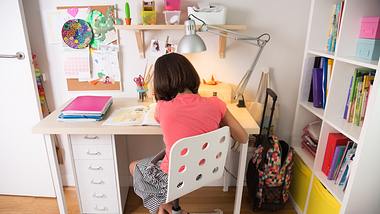 Mädchen sitzt an einem Schreibtisch für Kinder - Foto: iStock/ASIFE