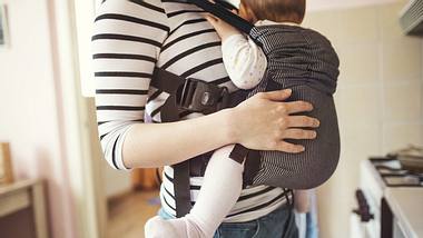 Mama mit Baby in Babytrage - Foto: iStock/halfpoint