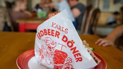 Karls Erdbeer-Döner in der Verpackung auf einem Tisch. - Foto: IMAGO / Eibner Karls Erdbeer-Döner in der Verpackung auf einem Tisch. - Foto: IMAGO / Eibner