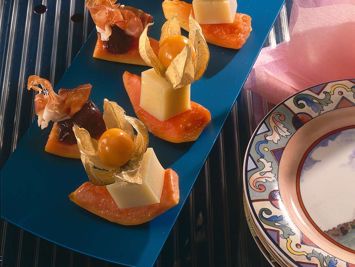 Käseplatte dekorieren: Käsewürfel auf Papaya mit Physalis