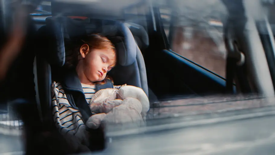 Kind im Auto vergessen Ein Kleinkind schläft im Kindersitz im Auto auf der Rückbank.