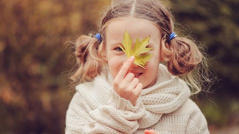 Kind hält sich ein Blatt vors Gesicht - Foto: Mkovalevskaya/iStock