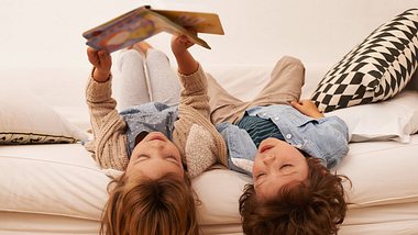 Kinder lesen Kinderbuch Klassiker auf Sofa - Foto: iStock/PeopleImages