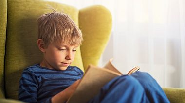 Ein kleiner Junge ließt ein Buch - Foto: Imgorthand / iStock