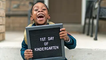 Lachender Junge mit Schild in den Händen auf dem 1st Day of Kindergarten - Foto: iStock/Fly View Productions Lachender Junge mit Schild in den Händen auf dem 1st Day of Kindergarten - Foto: iStock/Fly View Productions