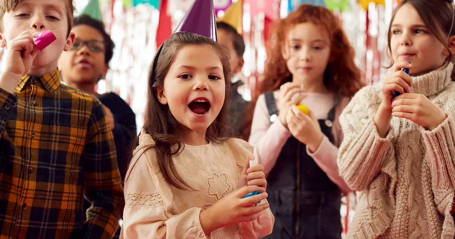Kindergeburtstag im Winter Gruppe von Kindergarten-Kindern mit Partyhütchen und Partybläsern, die Kindergeburtstag feiern