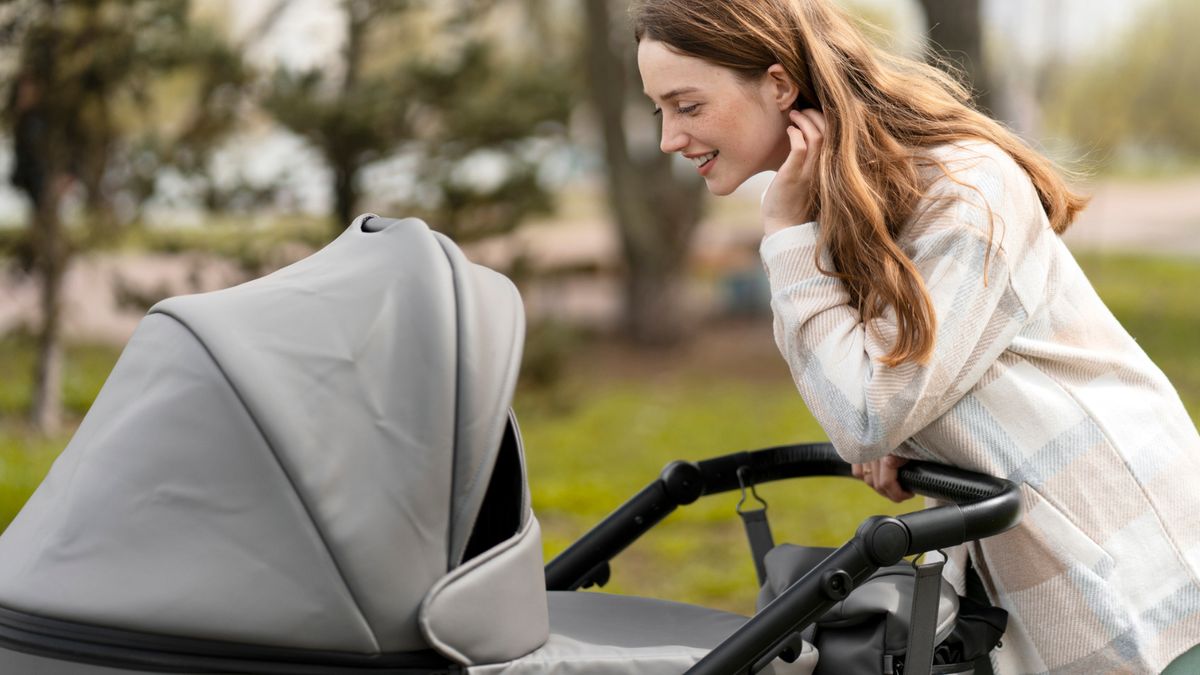 Frau beugt sich über einen Kinderwagen