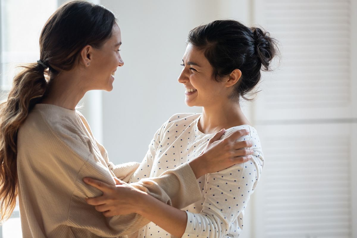 Zwei Frauen lachen sich liebevoll an und halten sich gegenseitig fest (Themenbild)