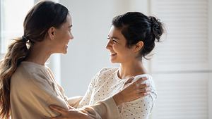 Zwei Frauen lachen sich liebevoll an und halten sich gegenseitig fest (Themenbild) - Foto: fizkes/iStock