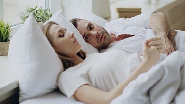 Frau und Mann im Bett, er hält ihre Hand - Foto: Credit: silverkblack/iStock (Themenbild)