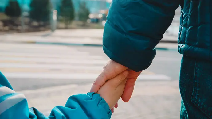 Bildausschnit kleines Kind hält die größere Hand eines Elternteils - Foto: iStock/Nadezhda1906
