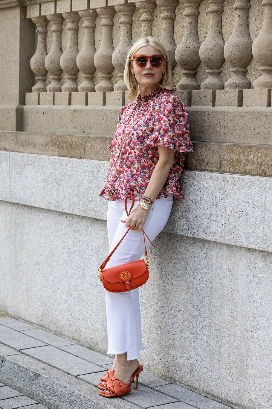 Lässig-elegante Kombination: Weiße Jeans mit Bluse Lässig-elegante Kombination: Weiße Jeans mit bunt gemusterter Bluse, in der Rot-Töne dominieren. Auch die Accessoires und Schuhe sind in Rot gehalten.