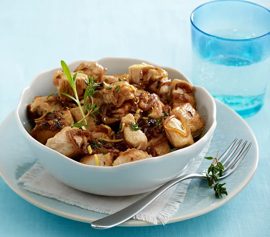 Leckeres Eiweiß-Rezept für zitroniges Putenragout Zitroniges Putenragout in einer Schüssel mit Thymian und Estragon garniert.