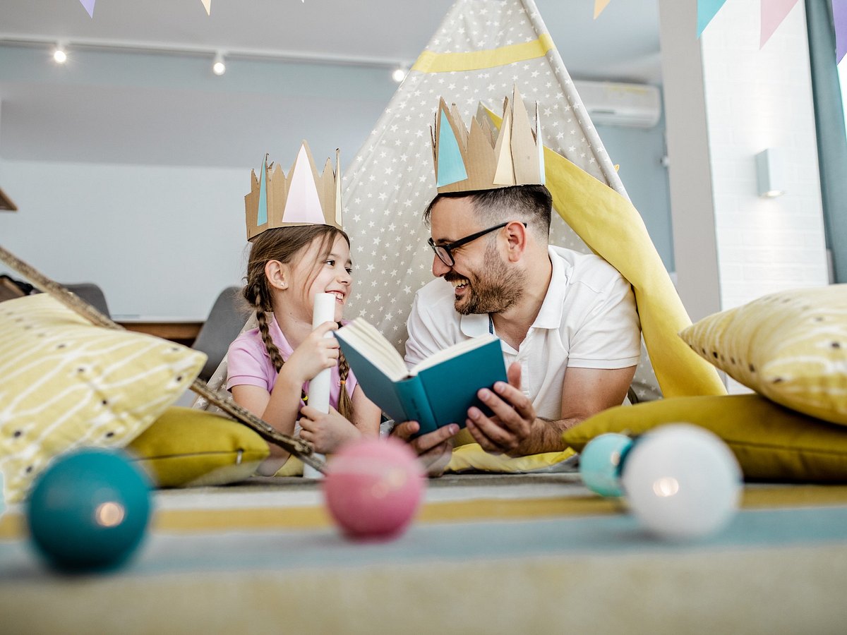 Vater und Tochter lesen Märchenbücher in Spielzelt