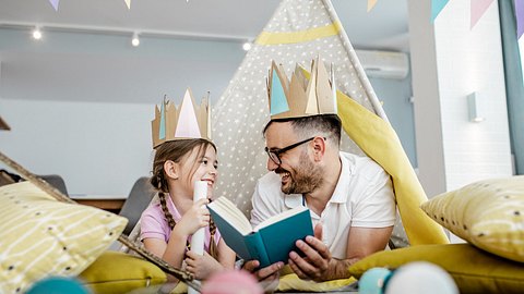 Vater und Tochter lesen Märchenbücher in Spielzelt - Foto: iStock/blackCAT