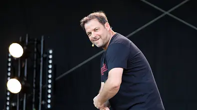 Martin Rütter steht vorgebeugt lächelnd auf der Bühne - Foto:  IMAGO / Karina Hessland