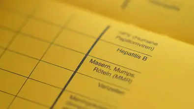 Aufgeschlagener Impfpass mit dem Fokus auf das Raster Masern, Mups und Röteln - Foto: iStock/Imagesines