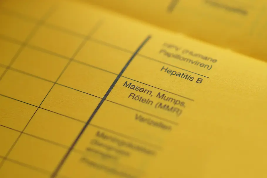 Hohe Bußgelder greifen bei einer fehlenden Masernschutzimpfung bei Kindern an Schulen Aufgeschlagener Impfpass mit dem Fokus auf das Raster Masern, Mups und Röteln