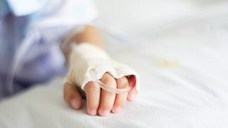 Hand eines Kindes mit Schlauch auf Krankenhausbett. - Foto: AgFang/iStock