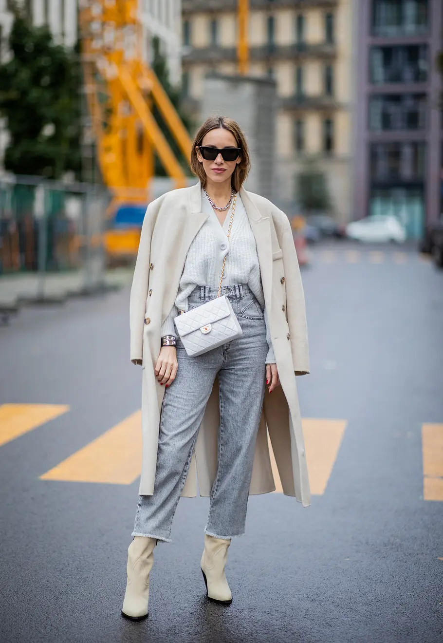 Mom Jeans Winter Kombis mit Must-Have Potenzial graue Jeans Frau mit grauer Mom Jeans, weißem Mantel, weißen Boots und weißem Cardigan