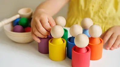 Nahaufnahme von Kinderhänden, die nach bunten Holzspielsachen greifen. - Foto: Maryna Auramchuk