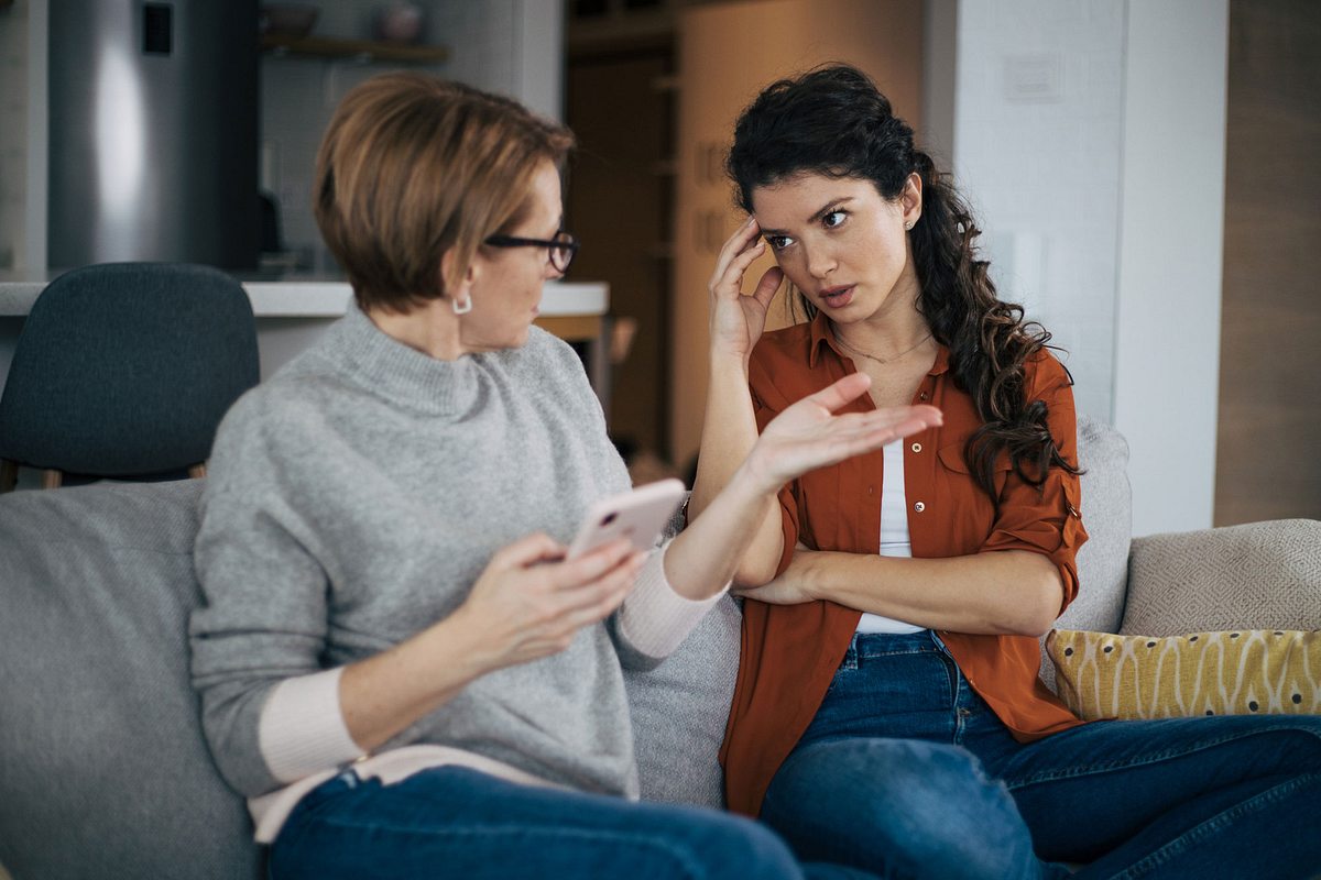 Mutter und Tochter diskutieren während sie auf dem Sofa sitzen.