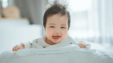 Kleines Baby mit wirrem Haar lacht in die Kamera (Themenbild) - Foto: oatawa/iStock